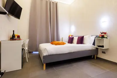 a bedroom with a bed and a table and a television at V Collection Vatican Jubilee Guest House in Rome