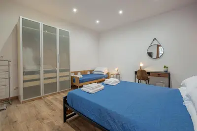 a bedroom with a blue bed and a desk at LE TRE M - Guesthouse in Rome