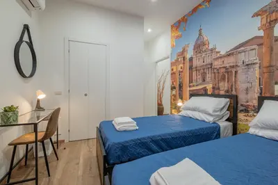 a bedroom with two beds and a desk and a painting on the wall at LE TRE M - Guesthouse in Rome