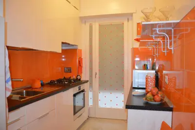 an orange kitchen with a sink and a refrigerator at Ad Maiora bb Roma Musei Vaticani in Rome