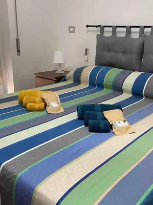 a bedroom with three beds with colorful striped sheets at La casetta di Matteo in Rome