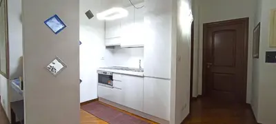 a small kitchen with white cabinets and a door at Colosseo Dream in Rome