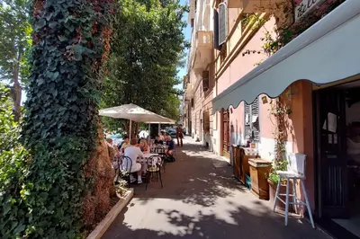a group of people sitting at tables under an umbrella on a street at dolce casa colosseo 2 in Rome