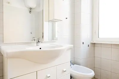 a white bathroom with a sink and a toilet at Pandolfo Apartment in Rome