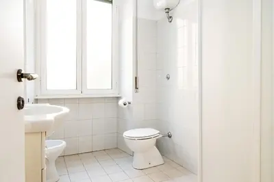 a white bathroom with a toilet and a sink at Pandolfo Apartment in Rome
