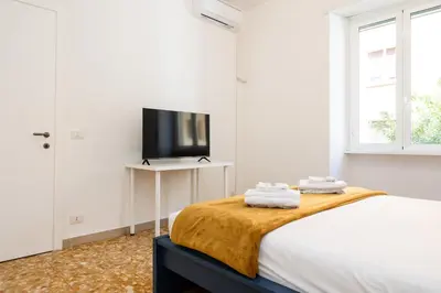 a white bedroom with a bed and a flat screen tv at Pandolfo Apartment in Rome
