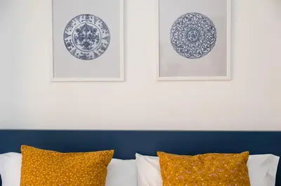 two framed plates on a wall above a bed with pillows at Pandolfo Apartment in Rome