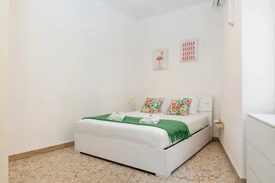 a white bedroom with a bed with a green blanket at Pandolfo Apartment in Rome