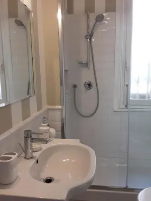 a white bathroom with a sink and a shower at L'Incantevole Aventino in Rome