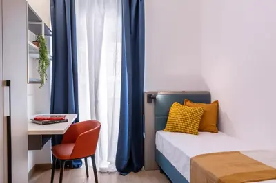 a bedroom with a bed and a desk and a chair at JOIVY Cavour 238 in Rome