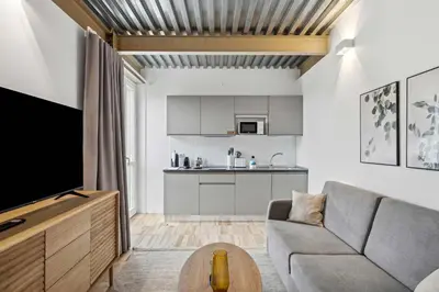 a living room with a couch and a tv and a kitchen at Limehome Rome Via Fortebraccio in Rome