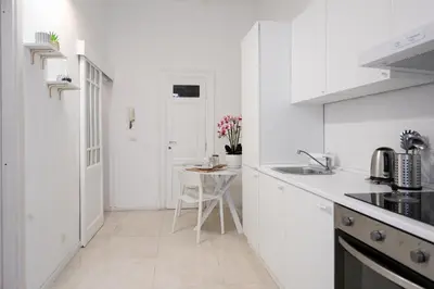 a white kitchen with a sink and a table at Ferrari 12 Apartment - Vaticano in Rome