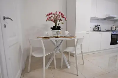 a white kitchen with a table with a vase of flowers at Ferrari 12 Apartment - Vaticano in Rome