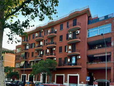 a red brick building with balconies on a street at MuMo Home - San Giovanni in Rome