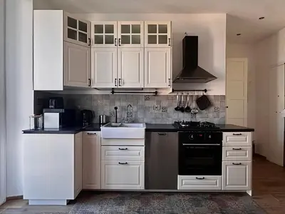 a kitchen with white cabinets and a black counter top at MuMo Home - San Giovanni in Rome