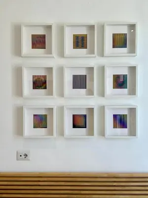 a wall with framed art on it with a bench at MuMo Home - San Giovanni in Rome