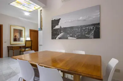 a dining room with a wooden table and white chairs at Navona New Deluxe Apartment in Rome