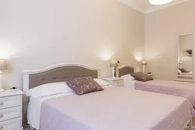 a white bedroom with two beds and a mirror at Aurora Guest House in Rome