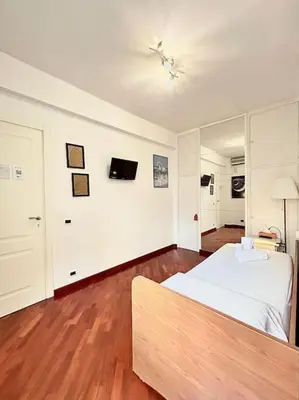 a bedroom with a white bed and wooden floors at Room Ostiense in Rome