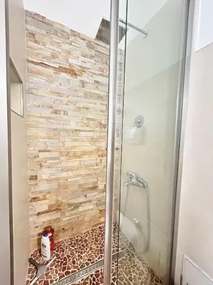 a bathroom with a shower with a stone wall at Room Ostiense in Rome