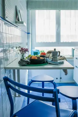 a blue kitchen with a table and two chairs at Milvio22 Apartment in Rome
