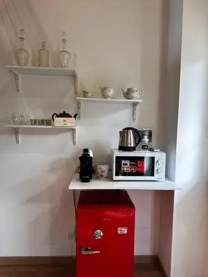 a small kitchen with a microwave and a red refrigerator at Casa Marlon Pietralata in Rome