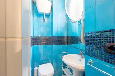 a blue tiled bathroom with a toilet and a sink at Tiny Steps to Piazza di Spagna in Rome