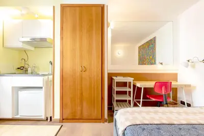 a bedroom with a bed and a desk and a kitchen at Tiny Steps to Piazza di Spagna in Rome