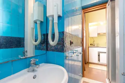 a blue tiled bathroom with a sink and a mirror at Tiny Steps to Piazza di Spagna in Rome
