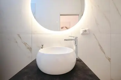 a white bathroom with a round sink and a mirror at 3' to Colosseum Bohèmien Paradise in Rome