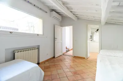 a white bedroom with two beds and a window at Terrazza Minerva in Rome