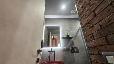 a bathroom with a red toilet and a brick wall at vatican street art in Rome