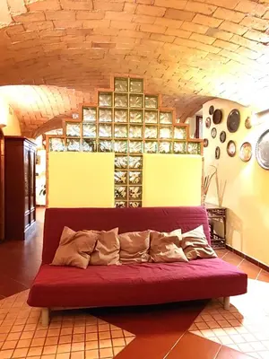a red couch in a room with a wall of wine bottles at San Giovanni Loft in Rome
