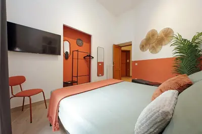 a bedroom with a bed and a chair and a tv at MAYA - Boutique Apartment in Rome