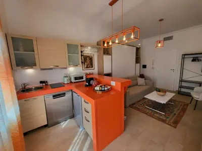 a kitchen with an orange counter top and a living room at Venus Inn Casa Vacanze AURELIA ANTICA in Rome