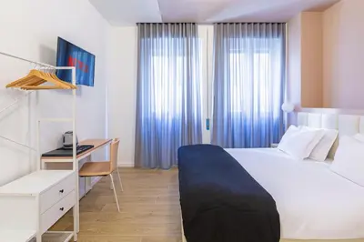 a bedroom with a white bed and a desk and window at Luciano Trastevere Guest House in Rome