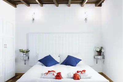 a white bed with blue pillows and red bows at Hub Navona in Rome