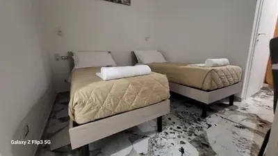 two beds in a small room with marble floors at Bed&Breakfast MENNA in Rome
