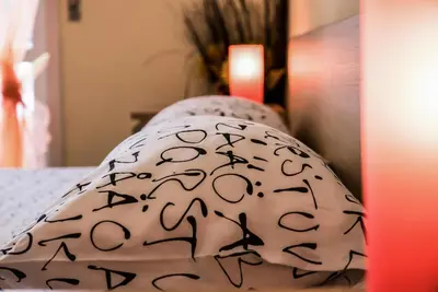 a white pillow with blackletters on a bed at A Place Apart in Rome