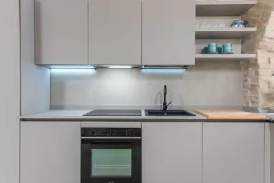 a kitchen with white cabinets and a black oven at DomusLatina Monti - Luxury stay in the heart of Rome in Rome