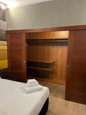 a room with a bed and a cabinet with towels on it at Colosseum Vibes in Rome