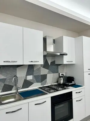 a white kitchen with a sink and a stove at Niva holiday house in Rome