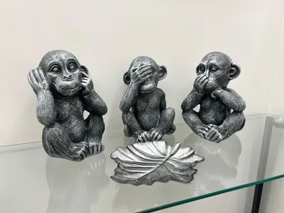 three statues of monkeys sitting on a glass table at Niva holiday house in Rome