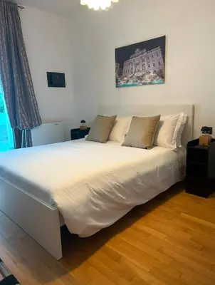a large white bed in a room with wooden floors at Dina Suite Rome in Rome