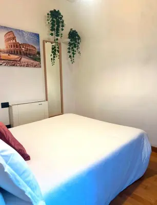 a bedroom with a white bed and a plant on the wall at Dina Suite Rome in Rome