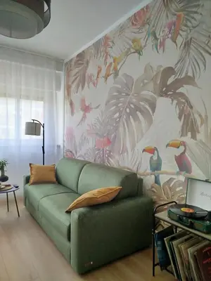 a living room with a green couch in front of a floral wall at Dylan Apartment in Rome