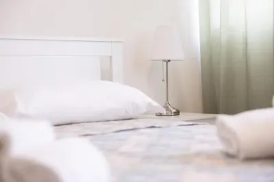 a white bedroom with a bed and a lamp at Dylan Apartment in Rome