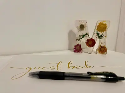 a pen on a table with flowers and a guest book at Suite Mario - Colosseo in Rome