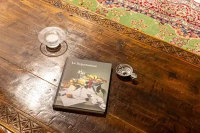 a book sitting on top of a wooden table with a glass at iFlat Pantheon Elegant 3-bedroom Apartment in Rome
