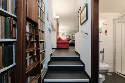 a hallway with bookshelves and a bathroom with a red couch at Casa Calligarich Stadio Olimpico Foro Italico in Rome